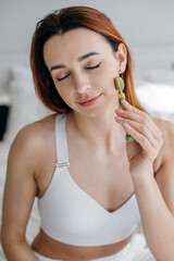 Young woman doing face massage with jade roller