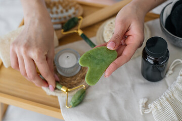 jade roller and gua sha stone in female hands