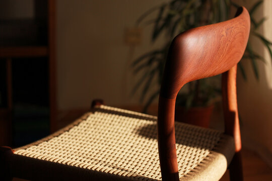 A danish mid century modern teak chair from the 60s vintage standing in the dining living room with paper cord seat teak wood 50s 70s retro original isolated on refurbished in living room closeup loft