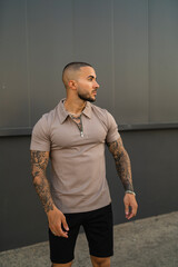 Chico joven musculoso y tatuado posando con ropa urbana