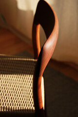 A danish mid century modern teak chair from the 60s vintage standing in the dining living room with paper cord seat teak wood 50s 70s retro original isolated on refurbished in living room closeup loft