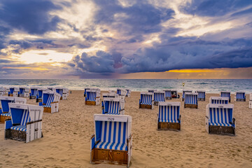 Fototapeta na wymiar Roofed wicker beach chairs on sunset at the North Sea coast on Sylt, Germany