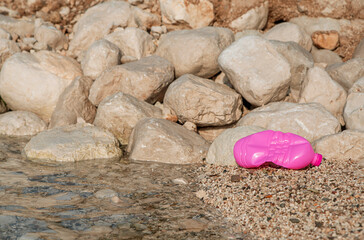 Beach pollution. Plastic bottle pink on the shore of the Adriatic Sea.