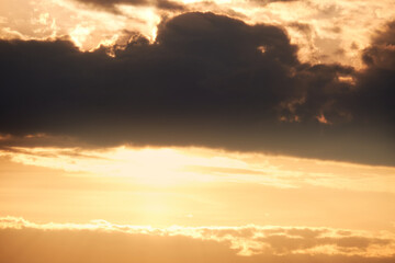 Fototapeta premium Dark clouds in the evening sunset sky with the setting sun. Dramatic sky during orange sunset