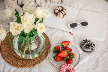 Home composition with a bouquet of flowers, strawberries and donuts.