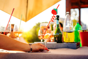 Naklejka na ściany i meble glass of alcoholic drink or soft drink at social gathering on sunny summer table, hand view