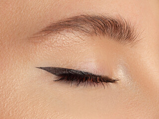 Cosmetics make-up. Beautiful female eye with sexy black liner makeup. Fashion big arrow shape on...