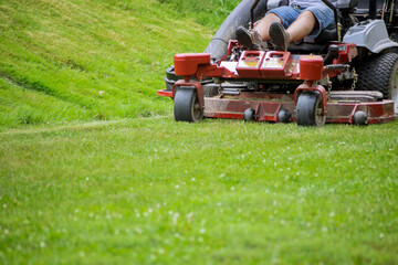 Man mows lawn using gasoline-powered self-propelled lawn mower on cutting grass with lawn mower.