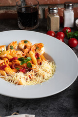 Penne Pasta with Shrimps, lemon and parmesan chhese on white plate on dark background, top view. Lemon pasta with sauteed shrimps, fresh seafood.