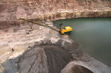 Walking dragline excavator in open pit on dolomite development. Big muskie in open-pit mining. Mining clay in quarry. Anthropogenic landscape with mountains in open cast mine. Limestone mining. .