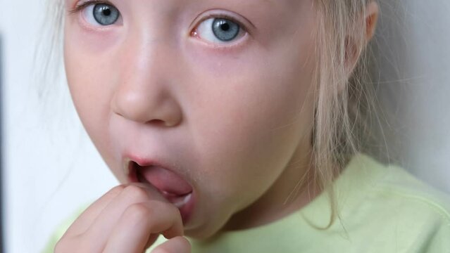 Portrait of a girl pulling out her baby tooth. Change of teeth. Loss of a baby tooth. The child's front tooth is loose. 