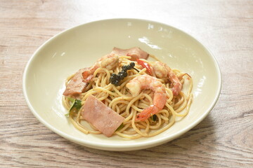 spicy stir fried spaghetti shrimp with slice ham pork and basil leaf on plate