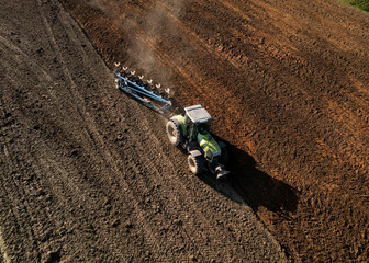 Tractor with plow on soil cultivating. Tractor plowing field, top view. Cultivated land and soil...