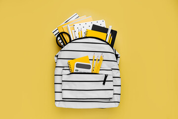 Opened School backpack with stationery on yellow background. Concept back to school. School...