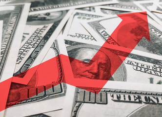 A bright red arrow against the background of money and Benjamin Franklin points up. The concept of changing the exchange rate of the US dollar in the market. Economic growth and currency strengthening