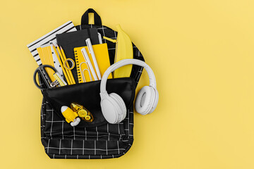 Opened School backpack with stationery on yellow background. Concept back to school. School...