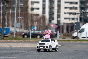 little girl drives a big white childrens electric toy car in the parking lot at the residential home © ako-photography