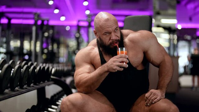 portrait of a male bodybuilder in sportswear, opening a freshly squeezed juice in training. replenishment of the body with vitamins and carbohydrates