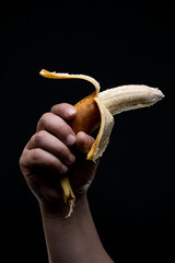 Yellow banana in male hands on a black background.