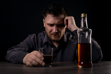 Lonely man drinks alcohol in the dark.