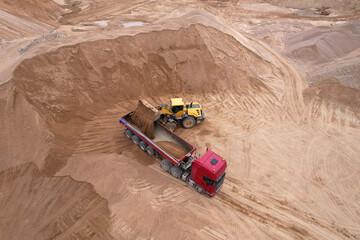 Wheel loader load sand in tipper truck in open pit. Front end loader on earthworks in open-pit...