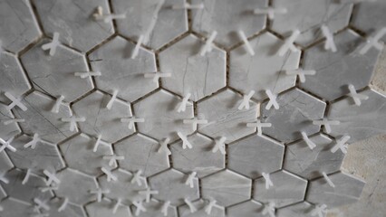A man lays a ceramic texture of hexagonal tiles on the wall. Ceramic hexagonal tiles on the wall.
