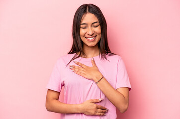 Young hispanic woman isolated on pink background laughs happily and has fun keeping hands on stomach.