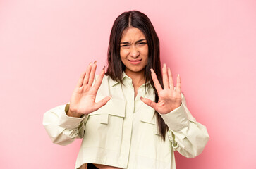 Young hispanic woman isolated on pink background rejecting someone showing a gesture of disgust.