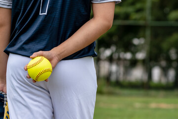 A young Softball player ready to peatch from his position in the outfield.holding a Softball ball in his hands while playing catch in the outfield