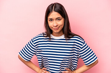 Young hispanic woman isolated on pink background sad, serious face, feeling miserable and displeased.