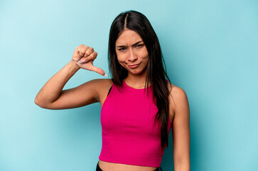 Young hispanic woman isolated on blue background showing thumb down, disappointment concept.
