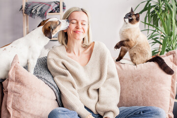 Happy woman playing with her dog on the couch at home