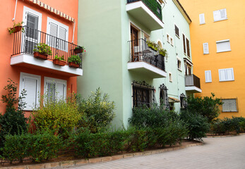 House with palm trees and flowers in yard. Colorful facade and door of the house with apartments at Port Saplaya. Landscape design at suburb home. Garden with flowers near house on street courtyard..