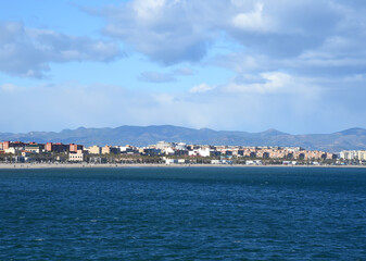 Fototapeta premium seascape of Mediterranean Sea. Coastline at Alboraya beach. View from sea to cityscape of Port Saplaya against the backdrop of the mountains. View blue seascape ocean. Coastal or coast view.
