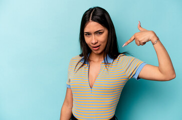 Young hispanic woman isolated on blue background person pointing by hand to a shirt copy space, proud and confident