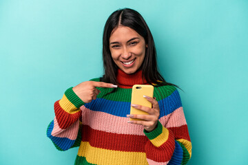 Young caucasian woman holding mobile phone isolated on blue background