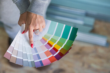Close-up of a female designer choosing paint samples for walls. A girl looks at a color sample to...