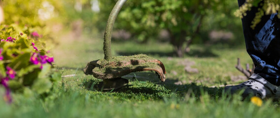 Banner. A human lawn mower cuts the grass in the backyard. Agricultural machinery for the care of the garden.