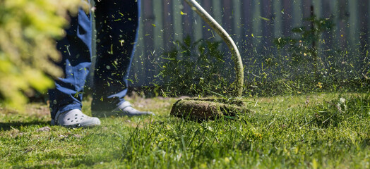 Banner. A human lawn mower cuts the grass in the backyard. Agricultural machinery for the care of the garden.