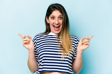 Young caucasian woman isolated on blue background pointing to different copy spaces, choosing one of them, showing with finger.