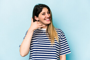 Fototapeta premium Young caucasian woman isolated on blue background showing a mobile phone call gesture with fingers.