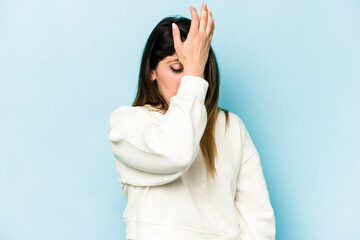 Young caucasian woman isolated on blue background forgetting something, slapping forehead with palm...