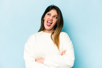Obraz premium Young caucasian woman isolated on blue background funny and friendly sticking out tongue.