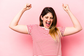 Young caucasian woman isolated on pink background raising fist after a victory, winner concept.