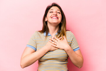 Young caucasian woman isolated on pink background laughing keeping hands on heart, concept of happiness.