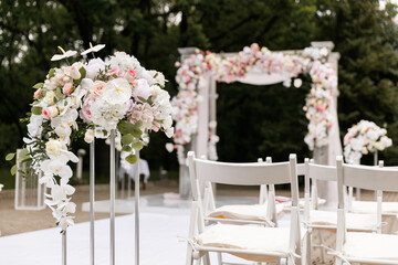 Wedding ceremony decorated with flowers and fabrics in light colors on the arch
