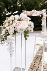 Wedding ceremony decorated with flowers and fabrics in light colors on the arch