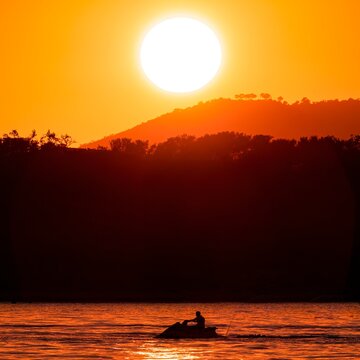 A jet ski on the sea with an orange sunset in the background