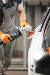 Car polishing in auto repair shop, close-up image.