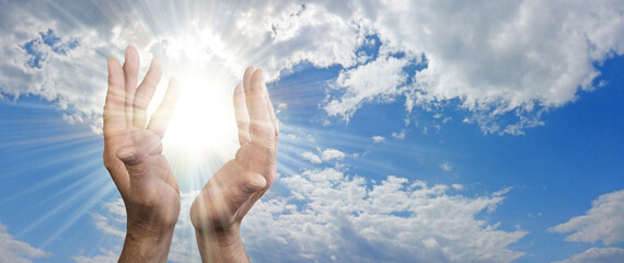 We wouldn't exist if the Sun didn’t Shine message banner - male hands appearing to capture sun burst between against a beautiful blue sky with fluffy clouds and space for copy 
